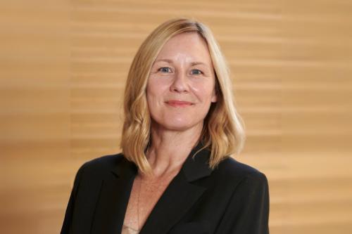 Amander Clark wears a dark blazer and smiles into the camera.