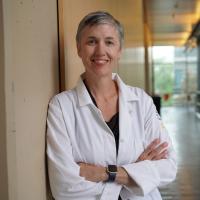 Female researcher with short grey hair wearing a white labcoat.