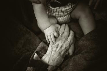 black and white photo of an infant holding an elderly woman's hand