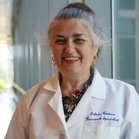 Female researcher with grey hair wearing a white lab coat.